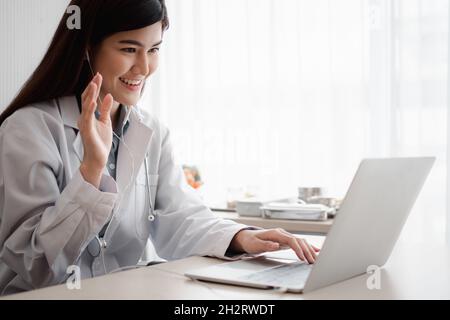 Femme thérapeute asiatique médecin est en ligne de visite avec un patient sur l'application Internet. Elle écoute et donne des conseils et explique comment traiter le Banque D'Images