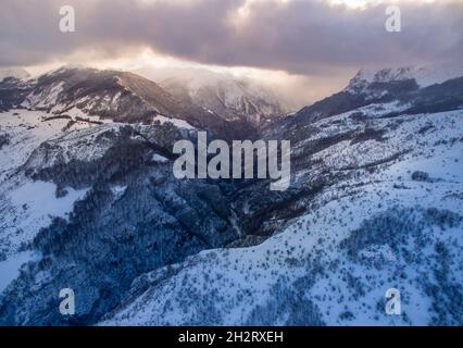 Une vue aérienne de la vallée enneigée de la montagne contre un ciel sombre Banque D'Images