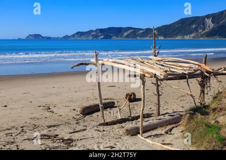 Tokomaru Bay, une plage isolée sur le Cap est de la Nouvelle-Zélande.Une petite structure en bois flotté se trouve au premier plan Banque D'Images