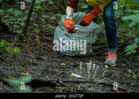 faites du nettoyage volontaire de la seringue usagée dans le parc et tenez-vous debout près d'une bande de sacs à ordures Banque D'Images