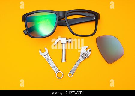 Lunettes de soleil brisées avec un ensemble d'outils à main sur fond jaune.Concept de service de réparation. Banque D'Images