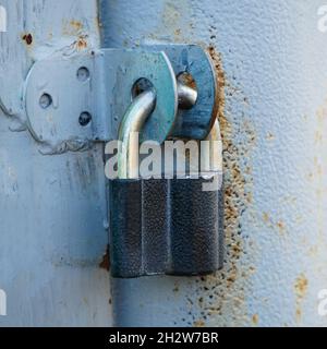 Cadenas fermé accroché aux charnières du fer gris porte Banque D'Images