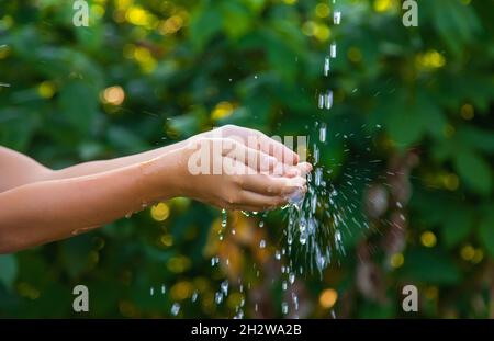 L'eau coule dans les mains de l'enfant.Mise au point sélective.Nature. Banque D'Images