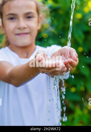 L'eau coule dans les mains de l'enfant.Mise au point sélective.Nature. Banque D'Images