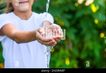 L'eau coule dans les mains de l'enfant.Mise au point sélective.Nature. Banque D'Images