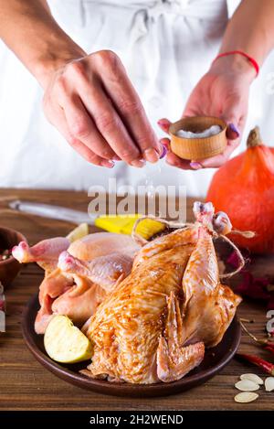 La femme au foyer prépare du poulet rôti Banque D'Images