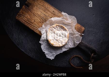 Camembert et brie sur planche à découper en bois sur fond sombre, vue du dessus.Cuisine italienne.Produits laitiers. Banque D'Images
