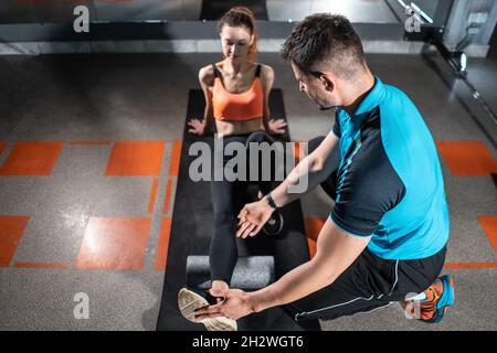 jeune femme se détendant avec un rouleau de relâchement myofascial avec entraîneur dans la salle de gym Banque D'Images