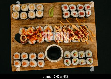 La composition de l'ensemble de sushis maki avec sauce au gingembre, au wasabi et au soja est servie sur un comprimé en bois et sur une prise de vue d'en haut.Repas traditionnel japonais rool Banque D'Images