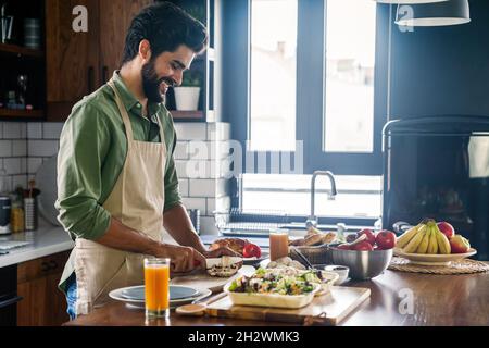 Bel homme cuisiner à la maison la préparation de salade en cuisine. Banque D'Images