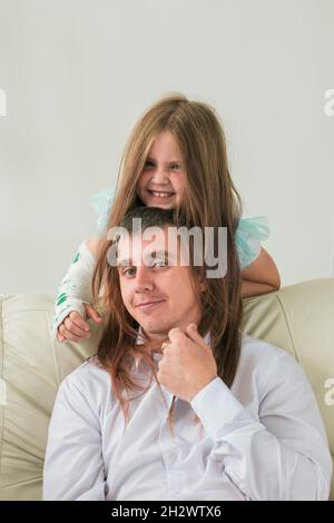 Père et sa fille s'amusent dans leur salon. Petite fille ont la main blessée mais elle est heureuse être ensemble son père. Banque D'Images