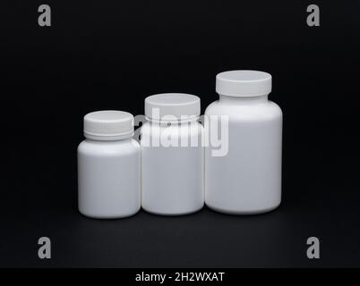 Pots de pilules en plastique blanc sur fond noir.Isolé Banque D'Images