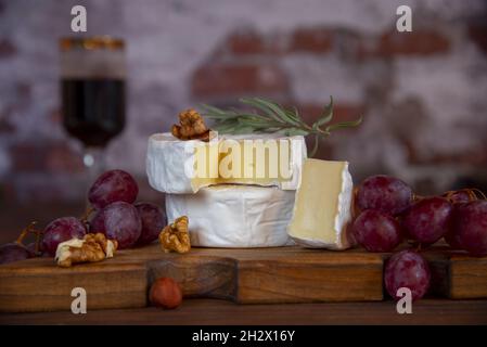 Fromage avec moule blanc, noix et raisins sur une planche à découper en bois.La nourriture. Banque D'Images