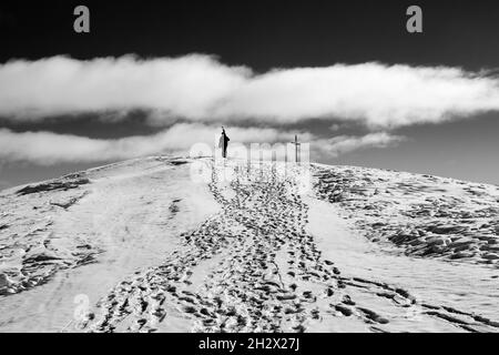 Silhouette de skieur avec des skis sur son épaule monter au sommet de la montagne en journée de soleil.Caucase montagnes en hiver, Géorgie, région de Gudauri, Mont Kudebi Banque D'Images