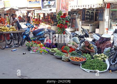 Beawar, Rajasthan, Inde, 23 octobre 2021 : les vendeurs indiens qui vendent des légumes et des fleurs artificielles attendent des clients sur un marché en amont du festival hindou de Beawar.Crédit : Sumit Saraswat/Alay Live News Banque D'Images