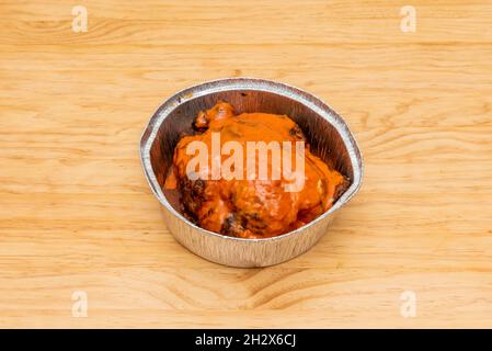 Poulet entier rôti au charbon de bois avec sauce au mojo picon sur le dessus dans un récipient à emporter en aluminium Banque D'Images