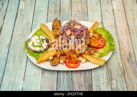 Plateau péruvien de gelée de fruits de mer avec manioc, moules battues, crevettes cuites et frites, pétoncles dans la sauce et légumes frais Banque D'Images