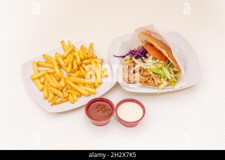Menu sandwich au kebab de poulet avec chou violet, tomate, oignon, pain pita, yaourt et sauce tomate et une portion de frites Banque D'Images