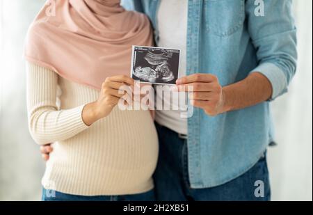 Premier portrait de notre bébé.Une femme enceinte musulmane heureuse et son mari montrant l'image de l'échogramme à l'appareil photo Banque D'Images