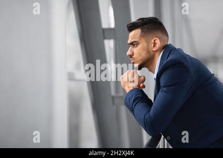 Portrait d'un homme d'affaires arabe réfléchi regardant de la fenêtre tout en attendant à l'aéroport