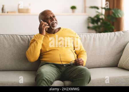 Homme afro-américain senior parlant sur téléphone portable assis à la maison Banque D'Images