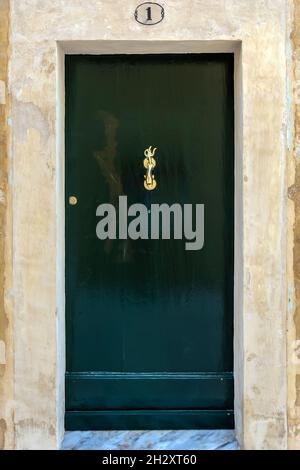 Porte en bois noir avec un knocker vintage en laiton comme dauphin avec une queue en forme de trident.Porte noire avec quincaillerie en cuivre moulé avec patine. Banque D'Images