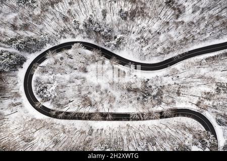 Route vide entourée de beaucoup de neige en hiver comme vue de fairytail d'en haut par drone. Banque D'Images