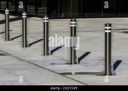 Poteaux de stationnement en acier pour empêcher le véhicule d'accéder à la chaussée.Résumé de cinq bollards métalliques avec lumière du soleil jetant des ombres linéaires.Dublin, Irlande Banque D'Images