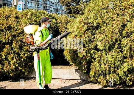 Dnepropetrovsk, Ukraine - 10.05.2021 : un employé du service municipal de la ville pulvérise des usines du paysage urbain. Banque D'Images