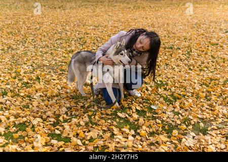 une jeune femme communique avec son chien au milieu du feuillage d'automne dans le parc Banque D'Images