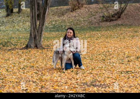 une jeune femme communique avec son chien au milieu du feuillage d'automne dans le parc Banque D'Images