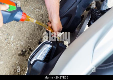 Réparation et entretien de motocycles.Un mécanicien de voiture verse de l'huile moteur dans un moteur de moto. Banque D'Images