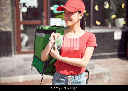 Femme de coursier transportant sac à dos thermique tout en faisant la livraison à l'extérieur Banque D'Images