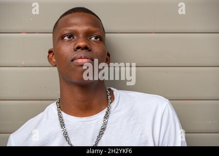 Jeune homme afro regardant contre un mur Banque D'Images