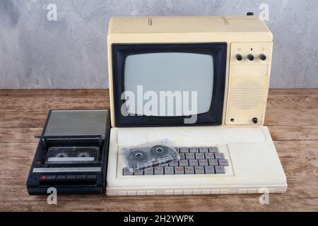 Rétro ordinateur personnel 8 bits avec enregistreur de données et moniteur de télévision sur un bureau en bois Banque D'Images