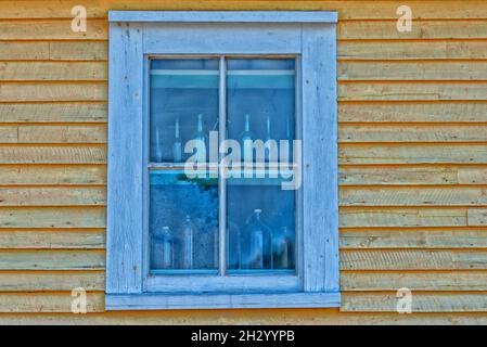 Le coin supérieur d'un bâtiment en bois jaune.Il y a une double fenêtre suspendue avec bordure blanche.Le bord du bâtiment est blanc. Banque D'Images