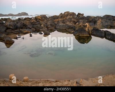 Couleurs de crépuscule, scène côtière.Le ciel bleu et rose pastel se reflète dans l'eau encore brillante des bassins de rochers sur la plage, en Australie Banque D'Images