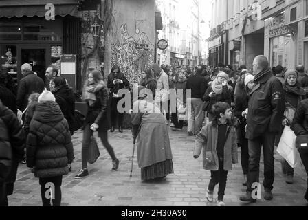 Une dame âgée est ignorée tout en mendiant dans les rues bondées du quartier juif de Paris Banque D'Images