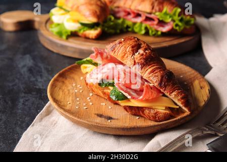 Assiette de délicieux croissants avec viande et fromage sur fond noir Banque D'Images