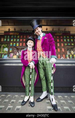 Willy Wonka (Ross Dawes) et Charlie (Troy Tipple) représentent un photocall devant une fabrique de chocolat en biscuit recréé par la comédie musicale West End et Biscuiteers, soutenus par Tate et Lyle, pour le 50e anniversaire de Charlie et de la chocolaterie Roald Dahl,Dans la vitrine Waterstones, Piccadilly, Londres. Banque D'Images