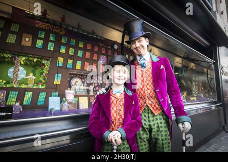 Willy Wonka (Ross Dawes) et Charlie (Troy Tipple) représentent un photocall devant une fabrique de chocolat en biscuit recréé par la comédie musicale West End et Biscuiteers, soutenus par Tate et Lyle, pour le 50e anniversaire de Charlie et de la chocolaterie Roald Dahl,Dans la vitrine Waterstones, Piccadilly, Londres. Banque D'Images