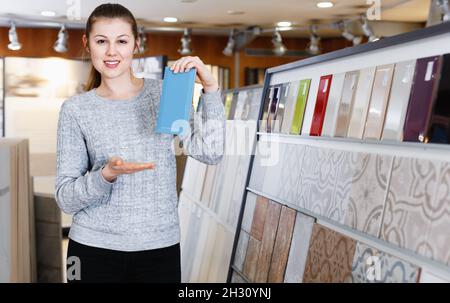 Portrait d'une femme regardant un échantillon de carreaux de céramique en magasin Banque D'Images