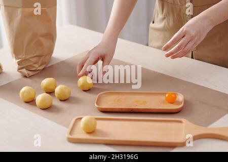 Image rapprochée d'une femme mettant des jaunes d'œufs salés dans la pâte lors de la cuisson de gâteaux de lune chez elle pour le festival de la mi-automne Banque D'Images