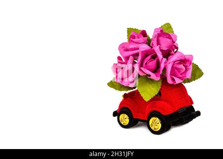 voiture jouet en velours rouge livrant bouquet de fleurs isolées sur fond blanc avec espace de copie.Carte de Saint-Valentin, anniversaire, 8 mars, International Banque D'Images
