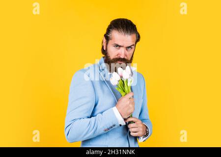 beau homme d'affaires caucasien avec la coiffure tendance en veste avec des fleurs de tulipe, cadeau Banque D'Images