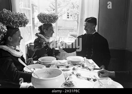 Eine Festtafel mit jungen Bräuten gekleidet in der traditionellen schwarzwälder Tracht mit dem Schäppel und ihren Bräutigamen, Deutschland 1930er Jahre.Un banquet avec de jeunes épouses portant la guirlande traditionnelle de la Forêt Noire avec le Schäppel et leurs grooms, Allemagne des années 1930. Banque D'Images