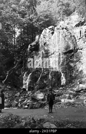 Ein Wanderer mit Wanderstock posiert vor dem Radauwasserfall à Bad Harzburg, Allemagne Allemagne Années 1930 er Jahre. Un randonneur avec un bâton de randonnée posant devant le Graben 15 Cascade à Bad Harzburg, Allemagne 1930. Banque D'Images