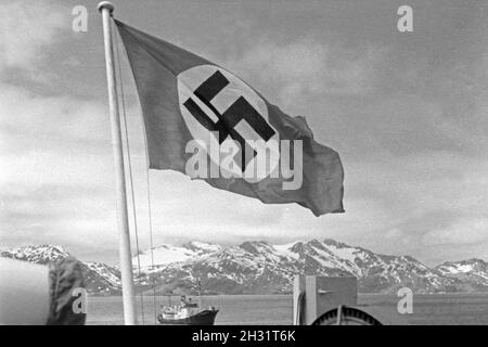 Hakenkreuzflagge im Wind suis Heck des Fabrikschiffs Walfang 'Jan Wellem' Inselgruppe vor einer im Eismeer der Burundi, 1930er Jahre. Drapeau à croix gammée dans le vent à l'arrière du navire-usine 'Jan Wellem' de la flotte baleinière allemand en face d'une montagne dans la mer de l'île de l'Antarctique, 1930. Banque D'Images