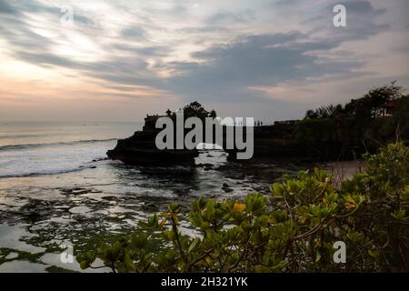 Silhouette du temple de Batu Bolong au coucher du soleil avec des nuages en fond bleu et orange à Tanah Lot, Bali, Indonésie.Personne. Banque D'Images