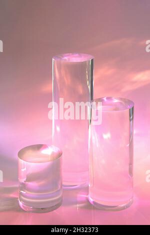 trois podiums en verre transparent sur fond rose pastel Banque D'Images